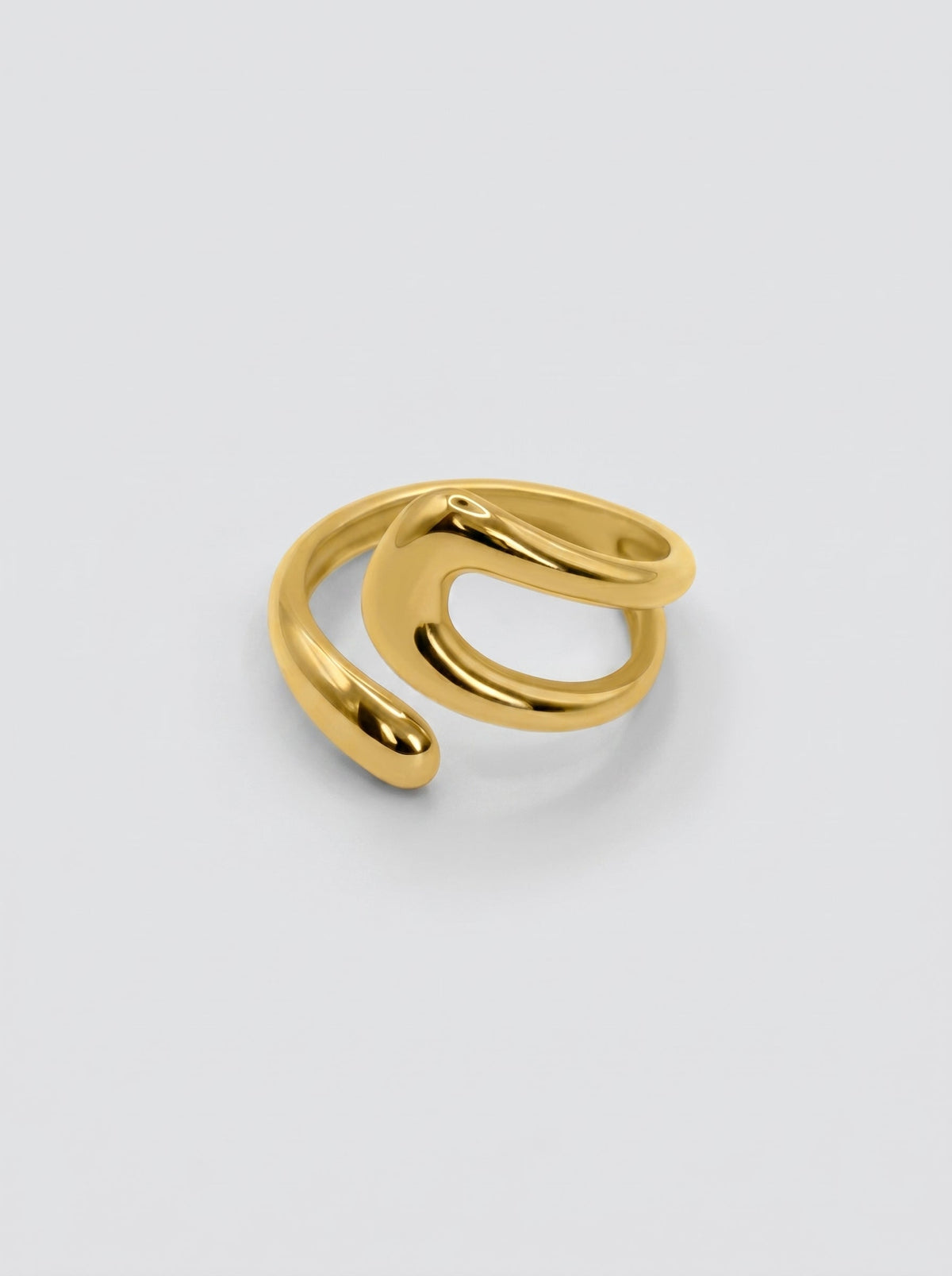Anillo dorado ajustable de forma fluida y moderna, con superficie pulida y diseño abierto sobre fondo neutro.