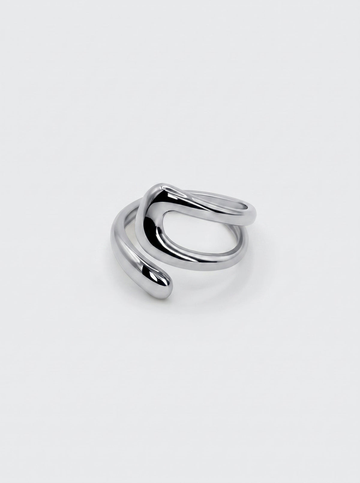 Anillo plateado ajustable de forma fluida y moderna, con superficie pulida y diseño abierto sobre fondo neutro.