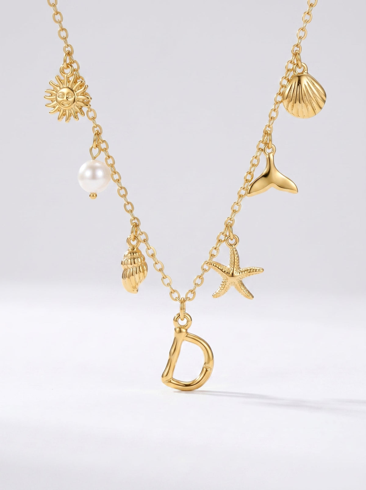 Collar dorado del mar con letra inicial D, estrella de mar, conchas, perla y colgante de sol.