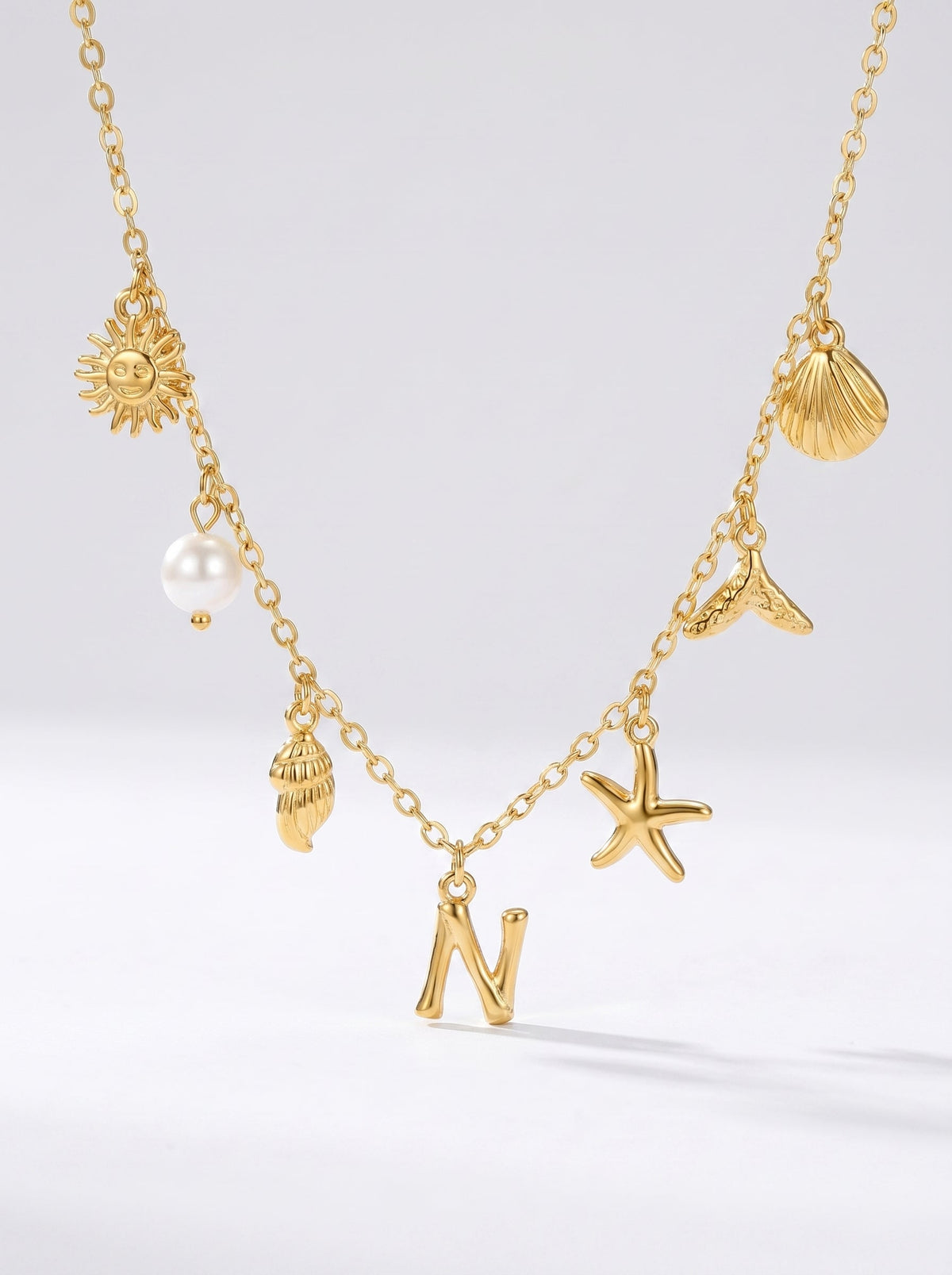 Collar dorado del mar con letra inicial N, estrella de mar, conchas, perla y colgante de sol.