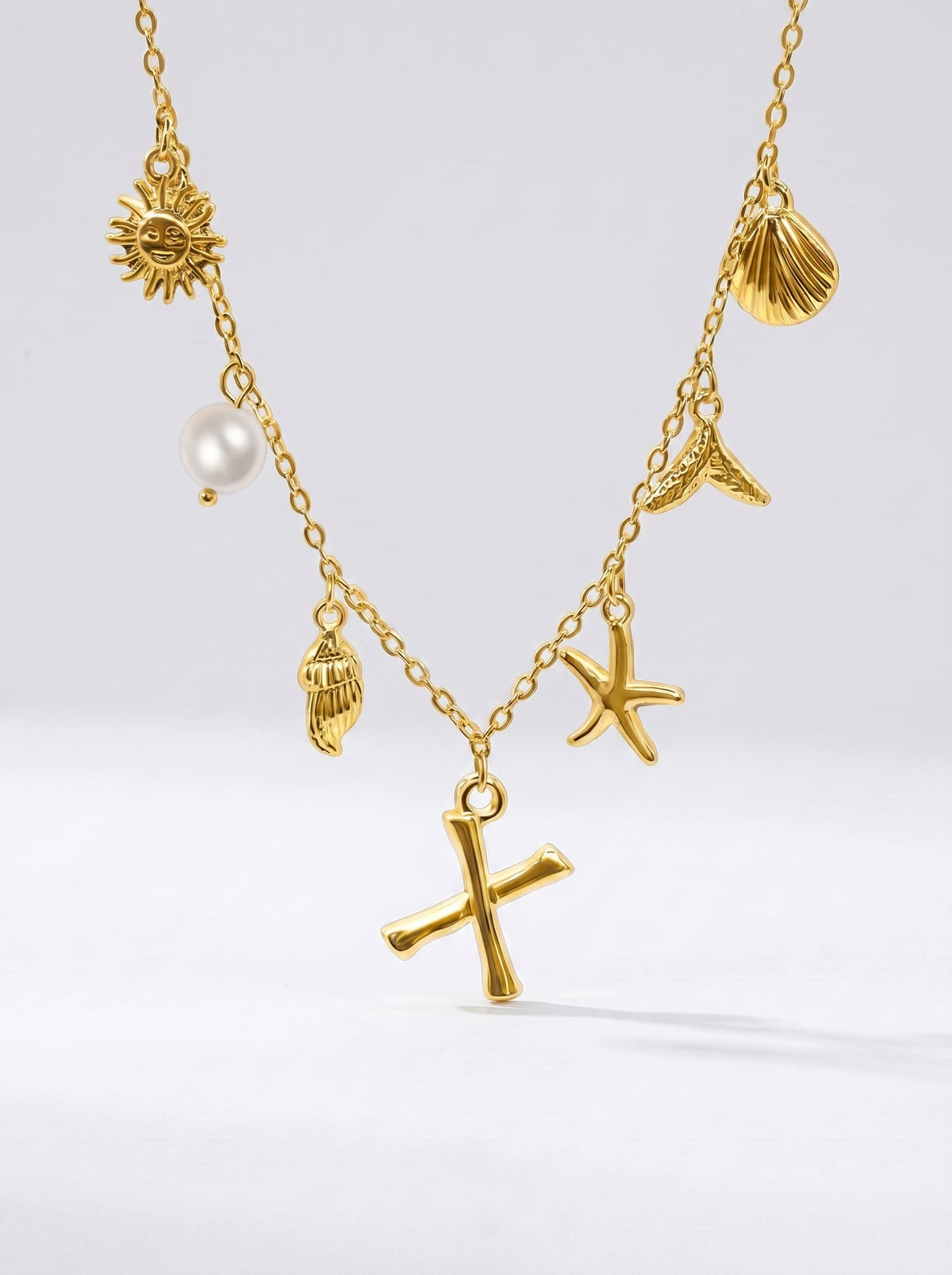 Collar dorado del mar con letra inicial X, estrella de mar, conchas, perla y colgante de sol.