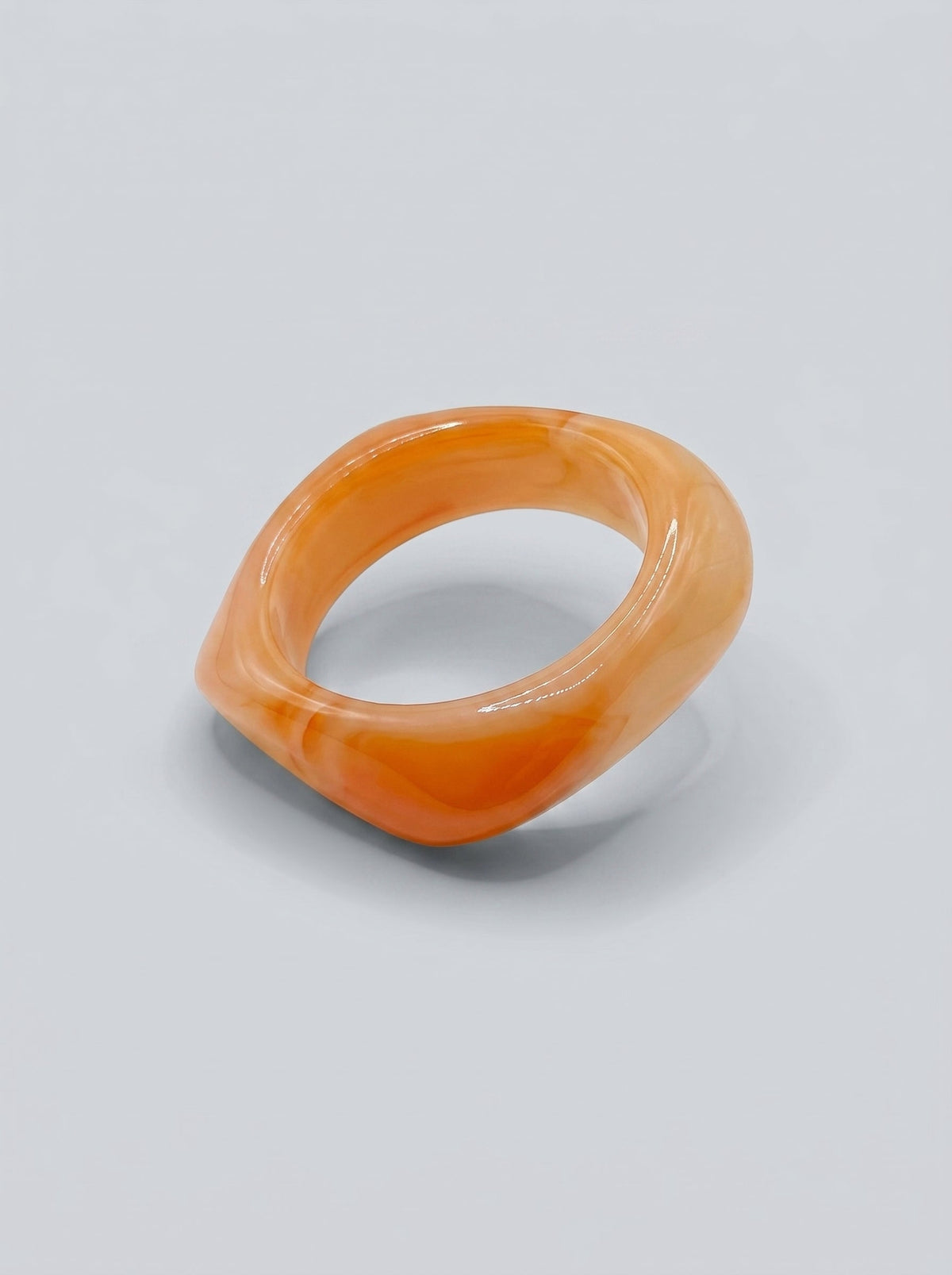 Pulsera Albaricoque en resina marmoleada en tonos albaricoque y coral suave, con diseño orgánico geométrico y acabado brillante, ideal para un look elegante y contemporáneo.
