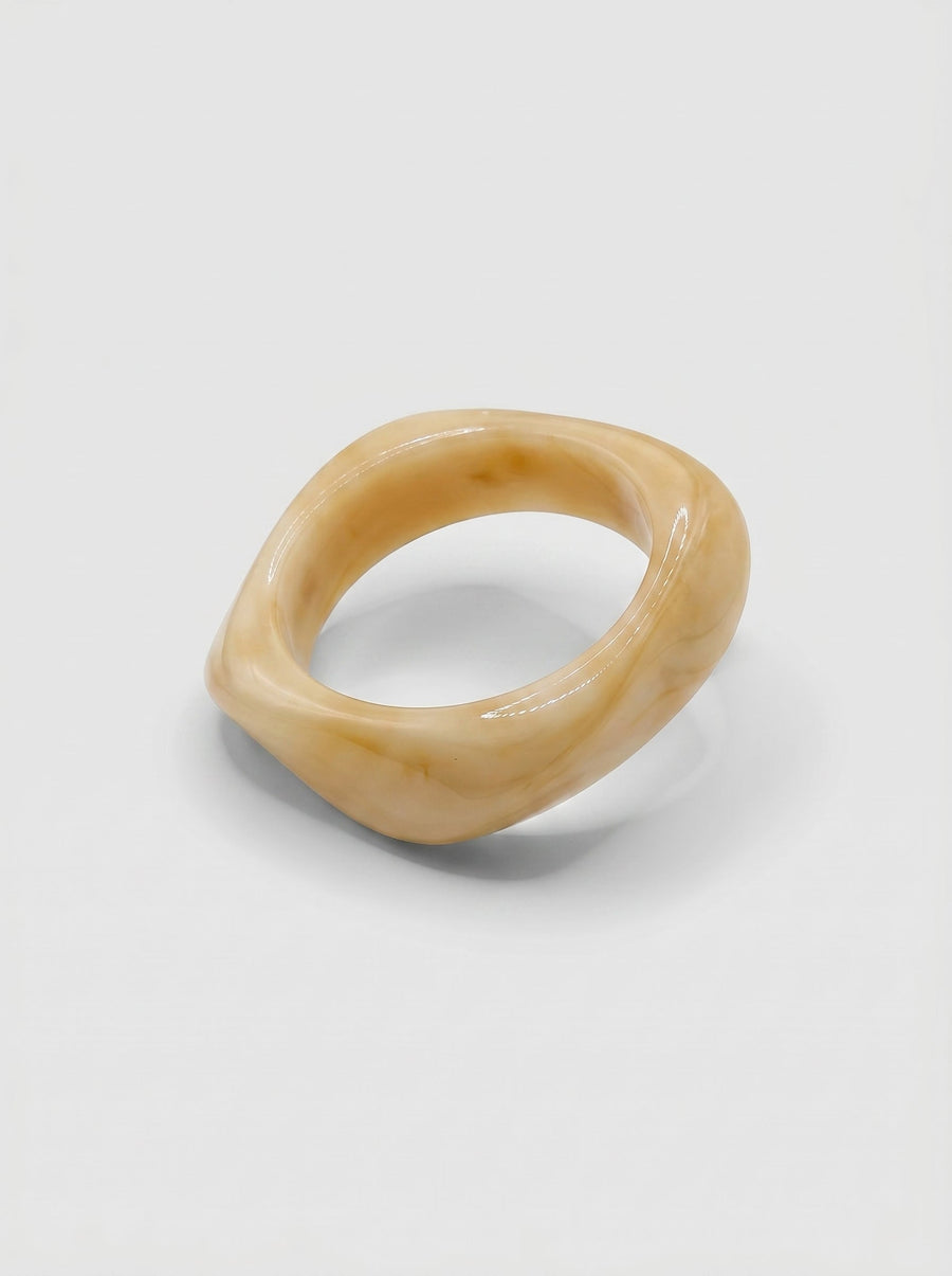 Pulsera Vainilla en resina marmoleada en tonos vainilla y crema, con diseño orgánico geométrico y acabado brillante, ideal para un look elegante y contemporáneo.