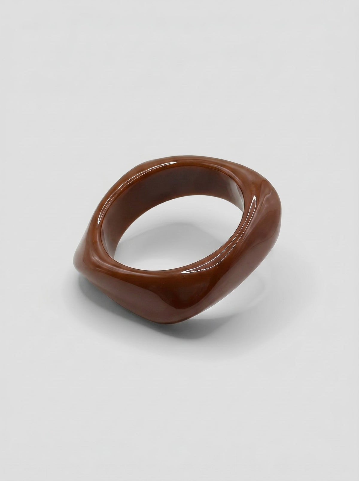 Pulsera Café en resina marmoleada en tonos café y marrón, con diseño orgánico geométrico y acabado brillante, ideal para un look elegante y contemporáneo.
