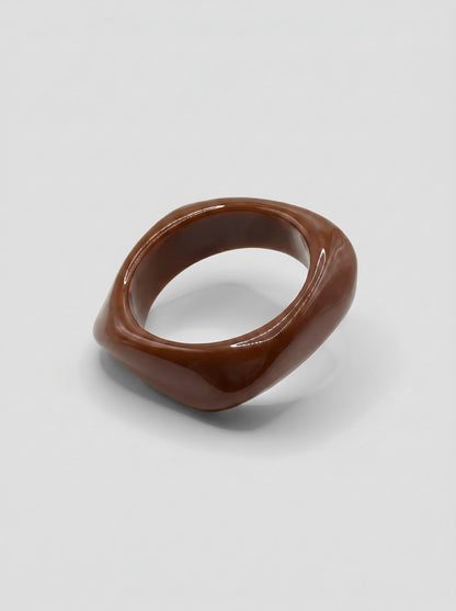 Pulsera Café en resina marmoleada en tonos café y marrón, con diseño orgánico geométrico y acabado brillante, ideal para un look elegante y contemporáneo.
