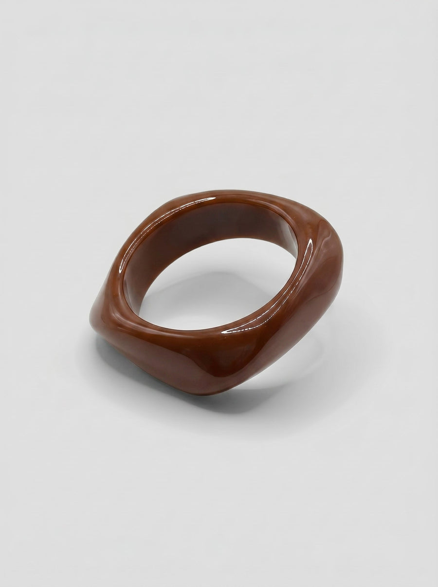 Pulsera Café en resina marmoleada en tonos café y marrón, con diseño orgánico geométrico y acabado brillante, ideal para un look elegante y contemporáneo.
