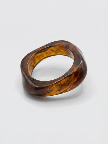 Pulsera Canela en resina marmoleada en tonos canela y ámbar oscuro, con diseño orgánico geométrico y acabado brillante, ideal para un look elegante y contemporáneo.