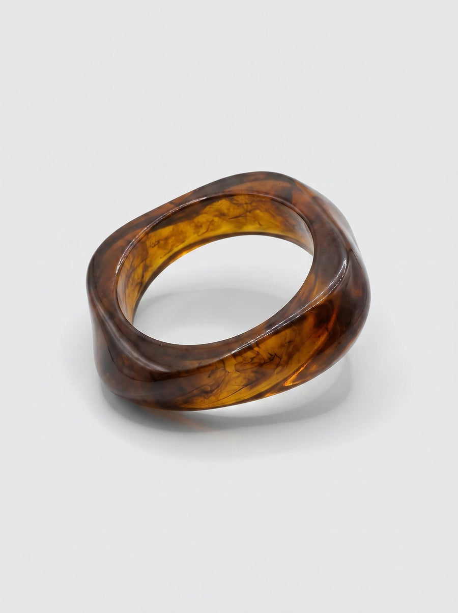 Pulsera Canela en resina marmoleada en tonos canela y ámbar oscuro, con diseño orgánico geométrico y acabado brillante, ideal para un look elegante y contemporáneo.