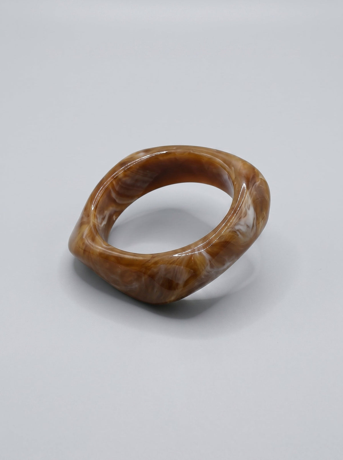 Pulsera Caramelo en resina marmoleada en tonos caramelo y dorado, con diseño orgánico geométrico y acabado brillante, ideal para un look elegante y contemporáneo.
