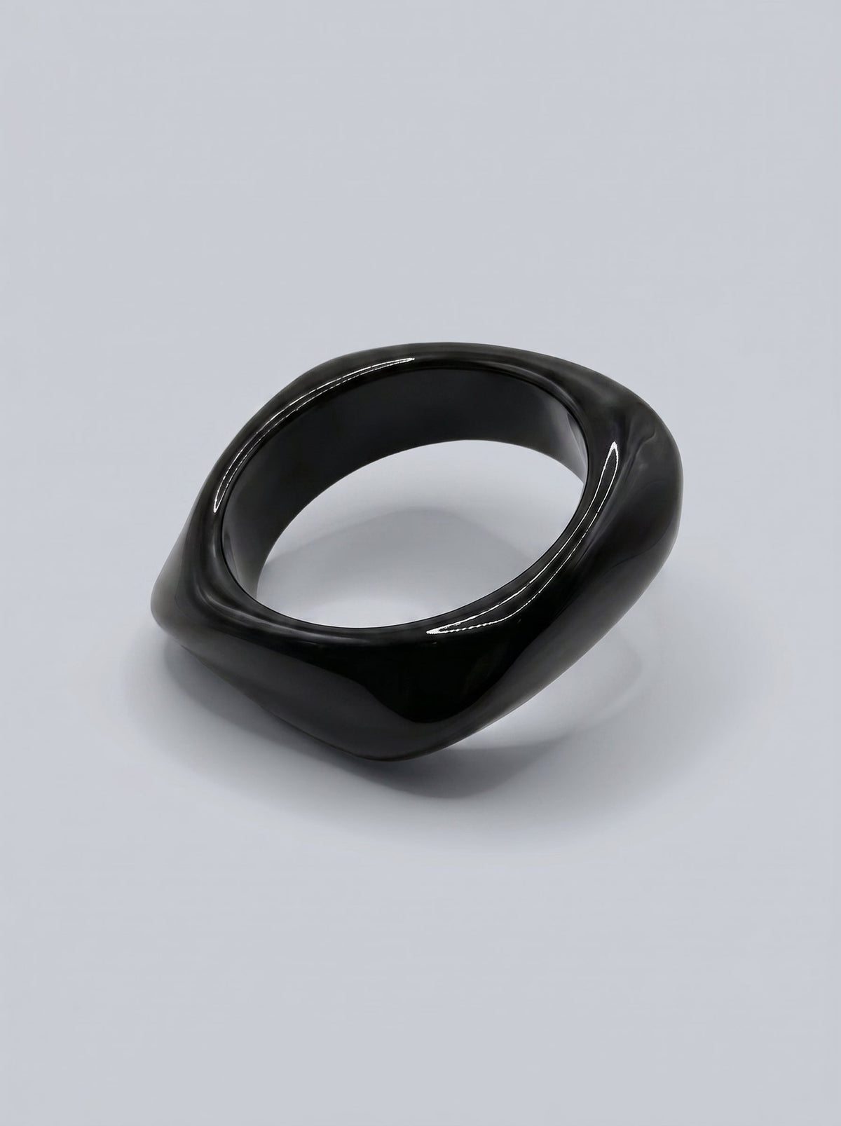 Pulsera Carbón en resina marmoleada en tonos carbón y gris oscuro, con diseño orgánico geométrico y acabado brillante, ideal para un look elegante y contemporáneo.
