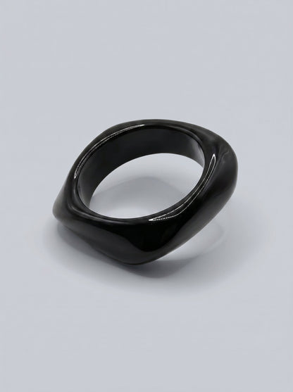 Pulsera Carbón en resina marmoleada en tonos carbón y gris oscuro, con diseño orgánico geométrico y acabado brillante, ideal para un look elegante y contemporáneo.

