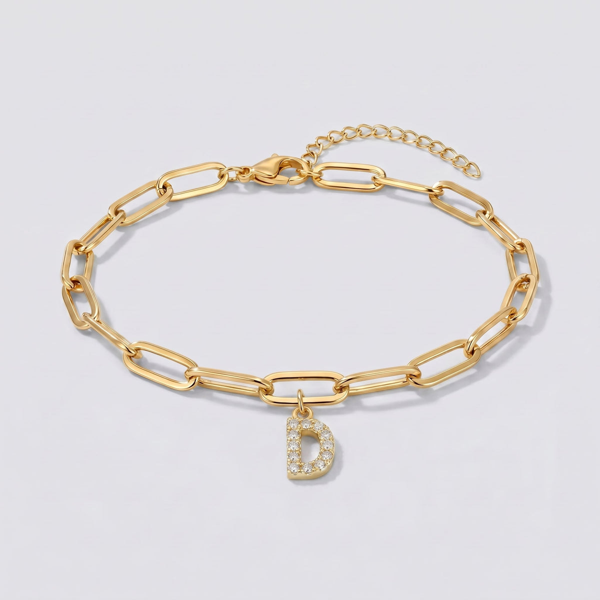 Pulsera dorada con letra inicial D, cadena paperclip y colgante de letra engastado.