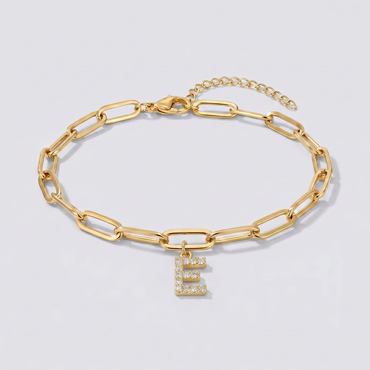 Pulsera dorada con letra inicial E, cadena paperclip y colgante de letra engastado.