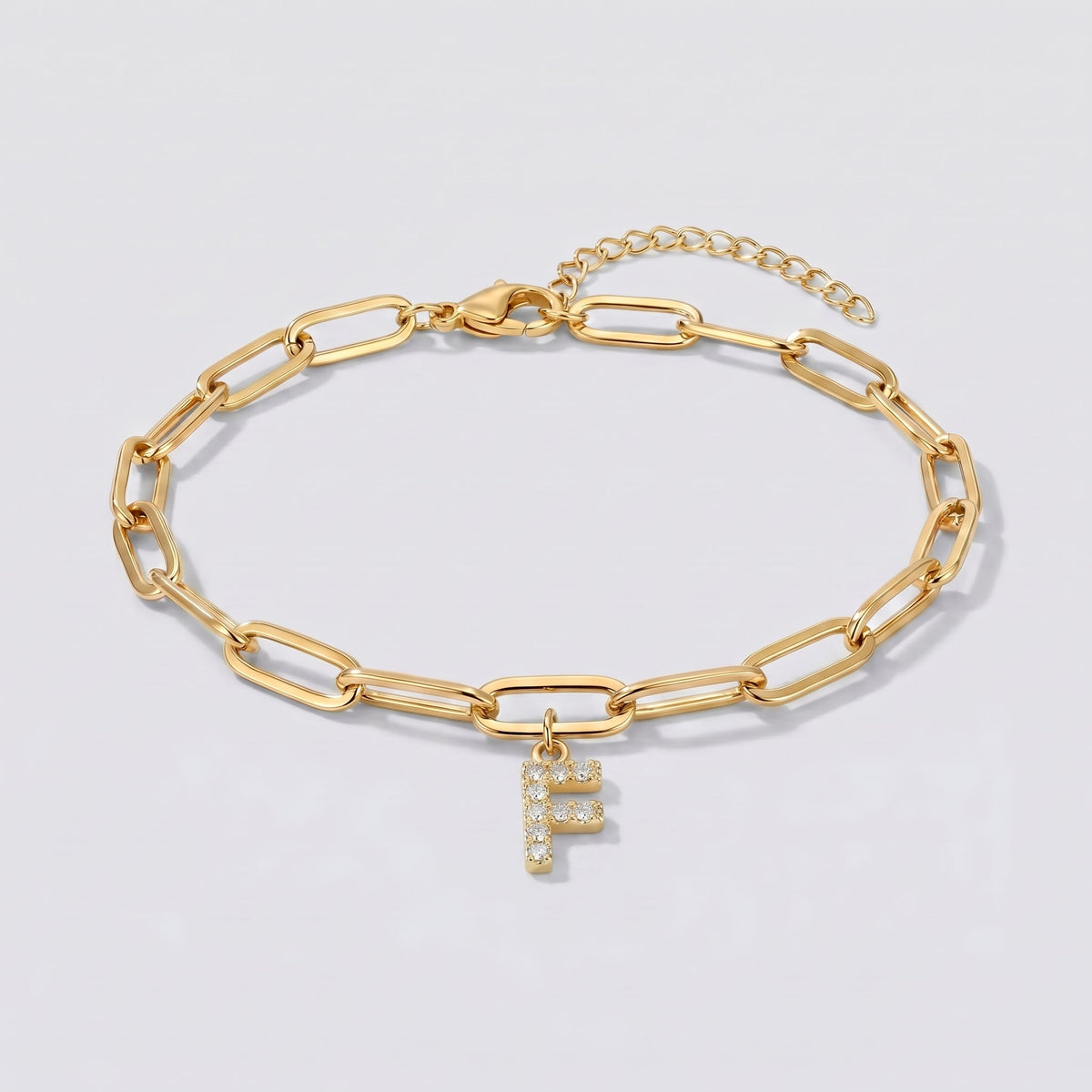 Pulsera dorada con letra inicial F, cadena paperclip y colgante de letra engastado.