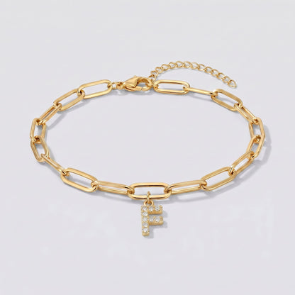 Pulsera dorada con letra inicial F, cadena paperclip y colgante de letra engastado.