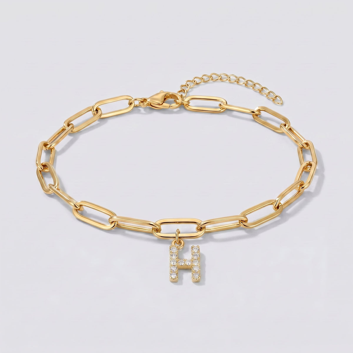 Pulsera dorada con letra inicial H, cadena paperclip y colgante de letra engastado.