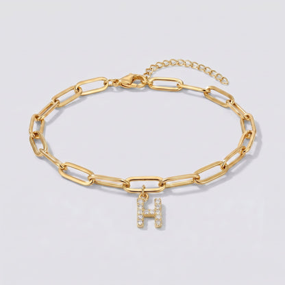 Pulsera dorada con letra inicial H, cadena paperclip y colgante de letra engastado.