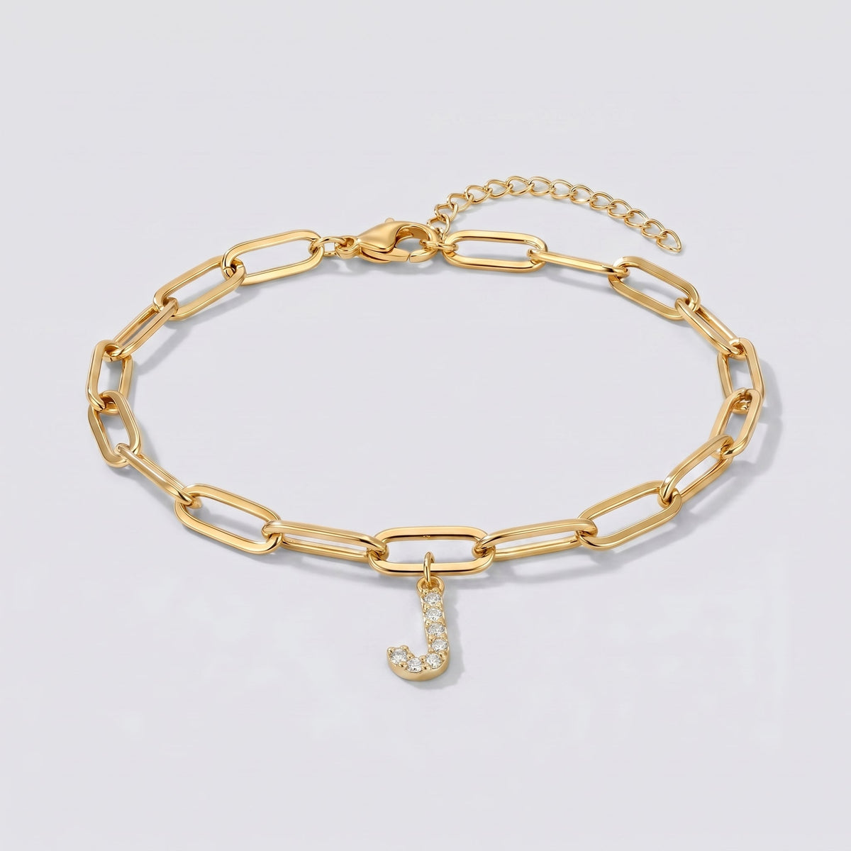 Pulsera dorada con letra inicial J, cadena paperclip y colgante de letra engastado.