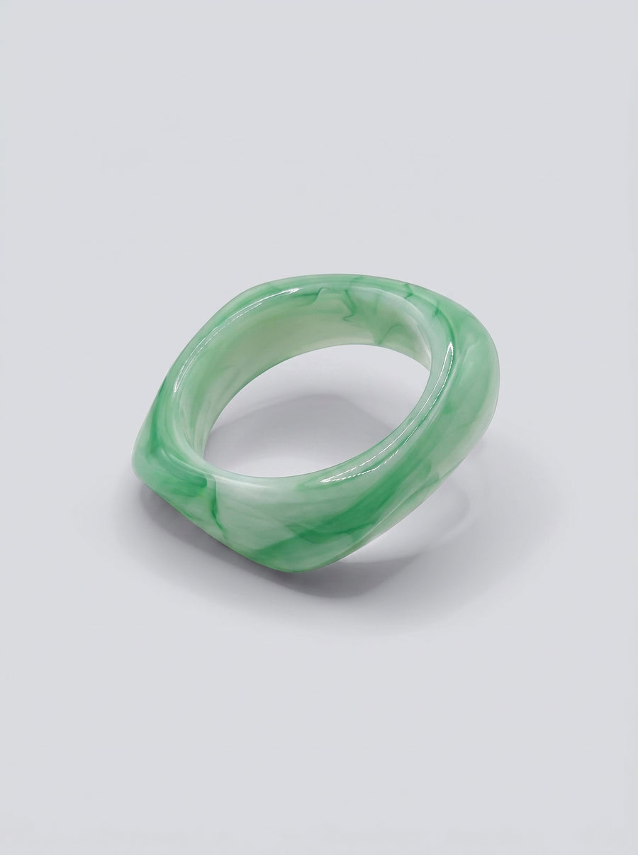 Pulsera Jade en resina marmoleada en tonos jade y verde suave, con diseño orgánico geométrico y acabado brillante, ideal para un look elegante y contemporáneo.
