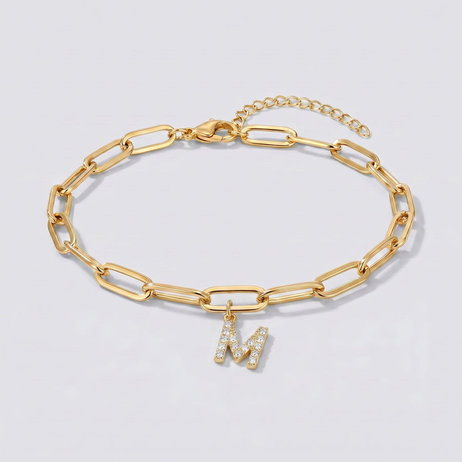 Pulsera dorada con letra inicial M, cadena paperclip y colgante de letra engastado.