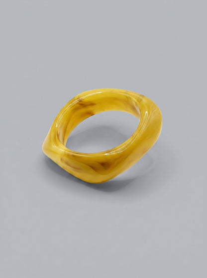 Pulsera Mostaza en resina marmoleada en tonos mostaza y amarillo dorado, con diseño orgánico geométrico y acabado brillante, ideal para un look elegante y contemporáneo.
