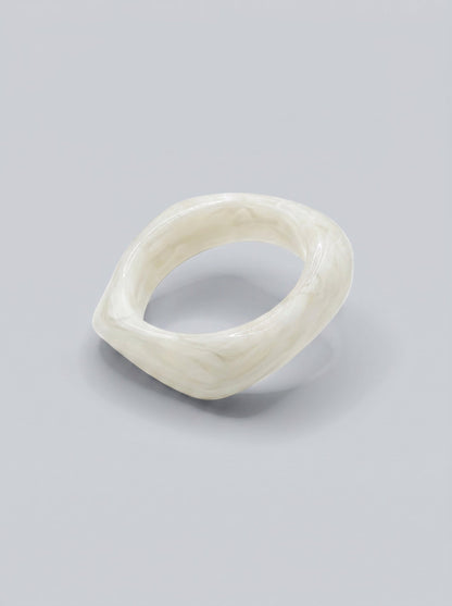 Pulsera Perla en resina marmoleada blanca, con diseño orgánico geométrico y acabado brillante, ideal para un look elegante y contemporáneo.