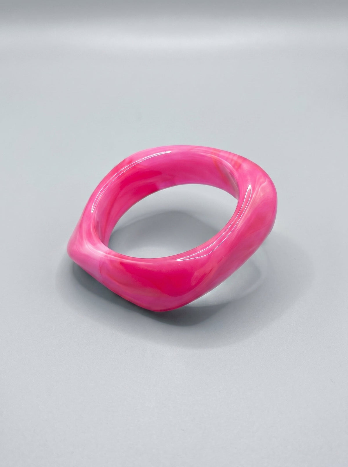 Pulsera de resina rosa marmolada, con forma rectangular y acabado brillante.