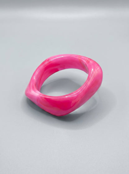 Pulsera de resina rosa marmolada, con forma rectangular y acabado brillante.