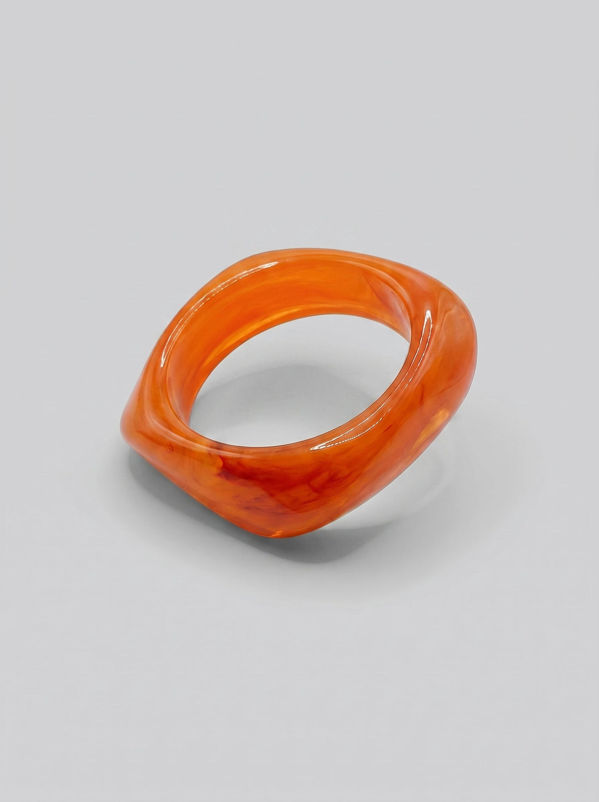 Pulsera Atardecer en resina marmoleada en tonos atardecer, coral y naranja, con diseño orgánico geométrico y acabado brillante, ideal para un look elegante y contemporáneo.