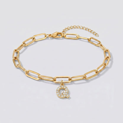Pulsera dorada con letra inicial Q, cadena paperclip y colgante de letra engastado.