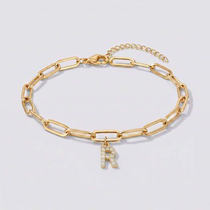 Pulsera dorada con letra inicial R, cadena paperclip y colgante de letra engastado.