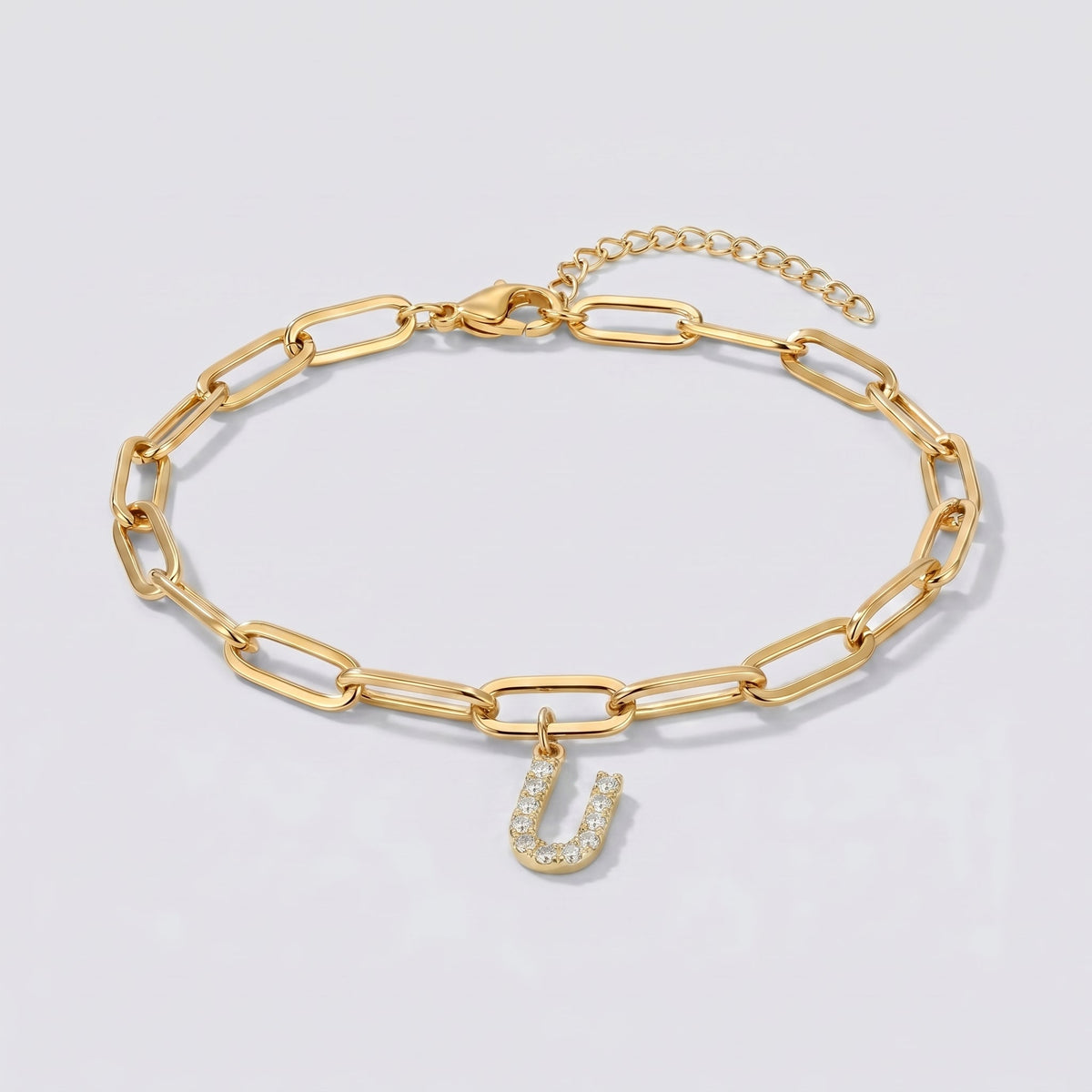 Pulsera dorada con letra inicial U, cadena paperclip y colgante de letra engastado.