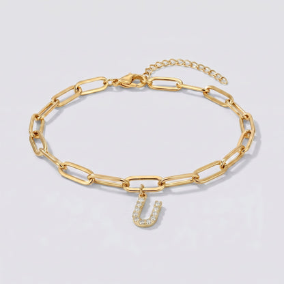Pulsera dorada con letra inicial U, cadena paperclip y colgante de letra engastado.