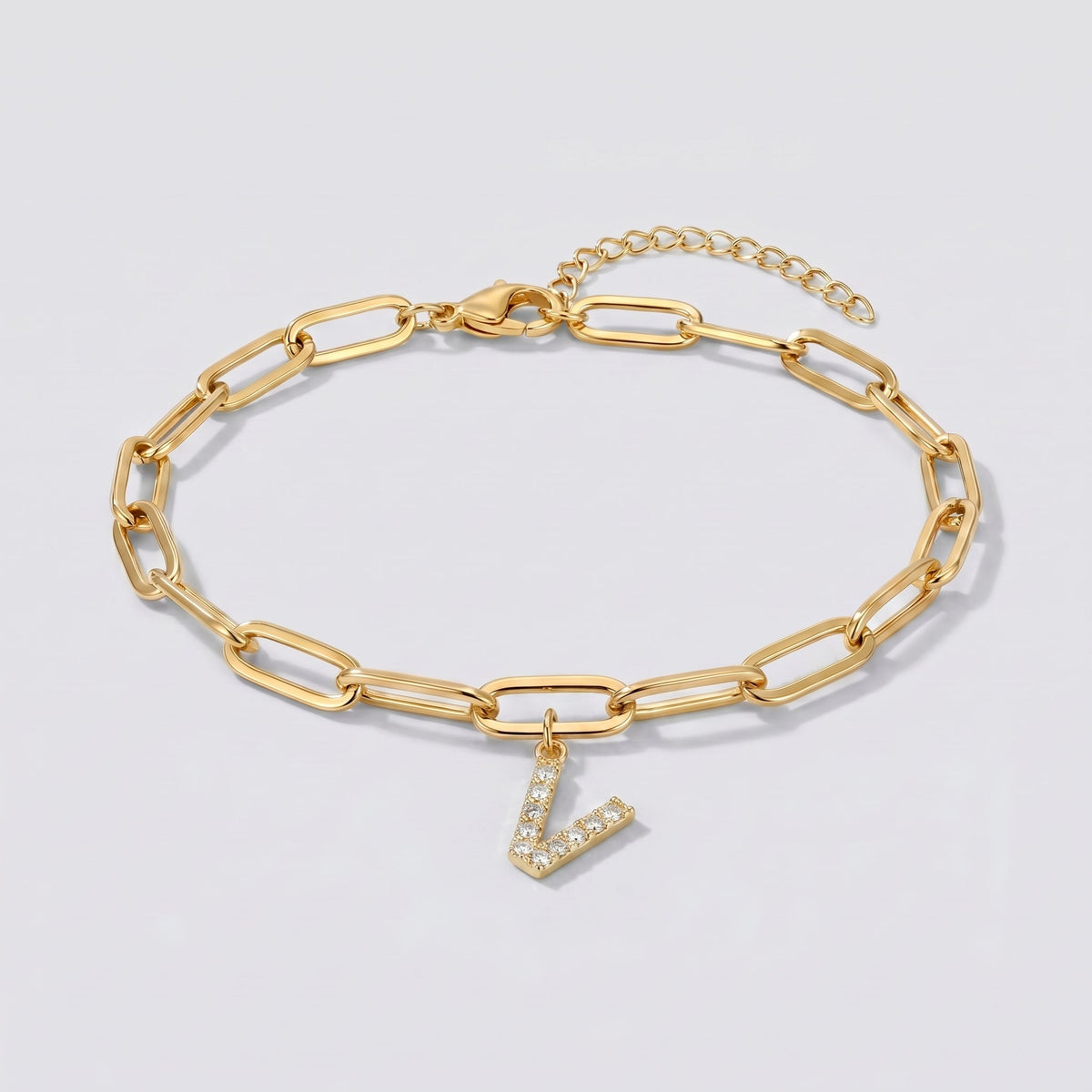 Pulsera dorada con letra inicial V, cadena paperclip y colgante de letra engastado.