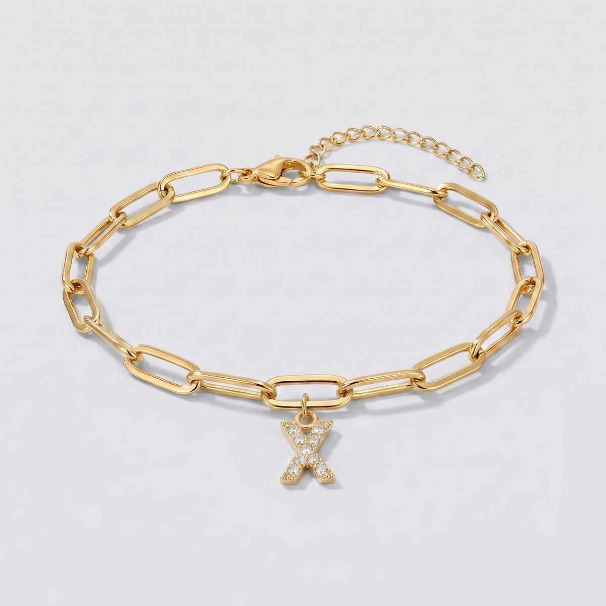 Pulsera dorada con letra inicial X, cadena paperclip y colgante de letra engastado.