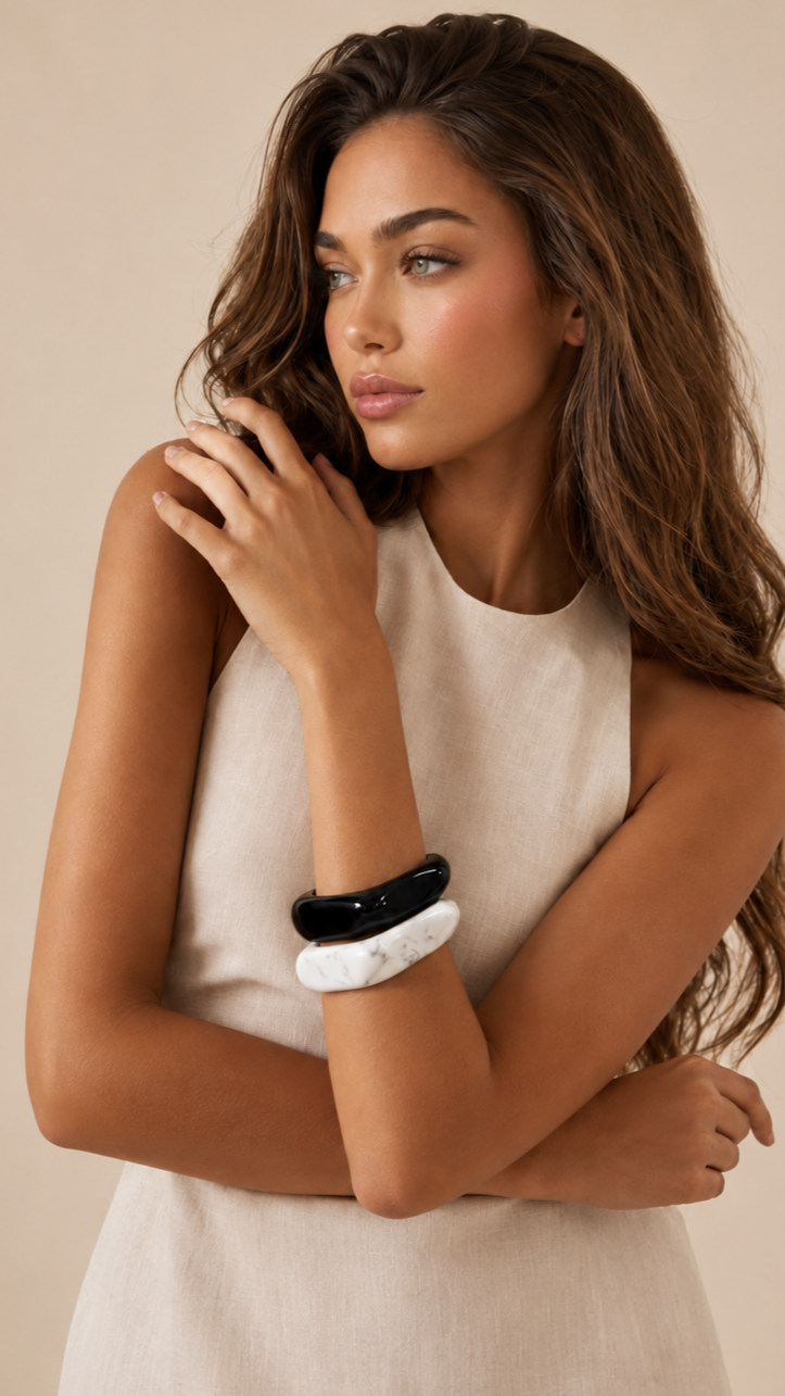 Pulseras de resina negra y blanca usadas por una modelo, con acabado brillante y estilo elegante.