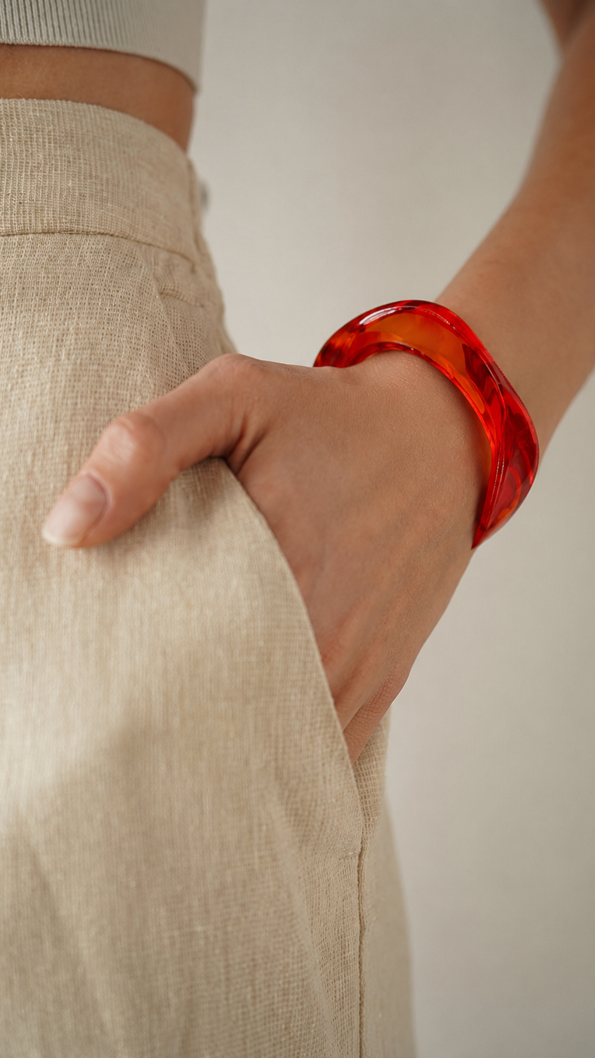 Pulsera de resina roja en la muñeca, con acabado brillante y estilo elegante.