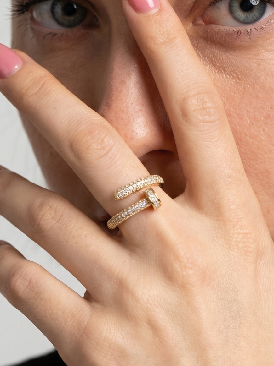 Primer plano de una mano con un anillo curvo dorado sobre fondo desenfocado
