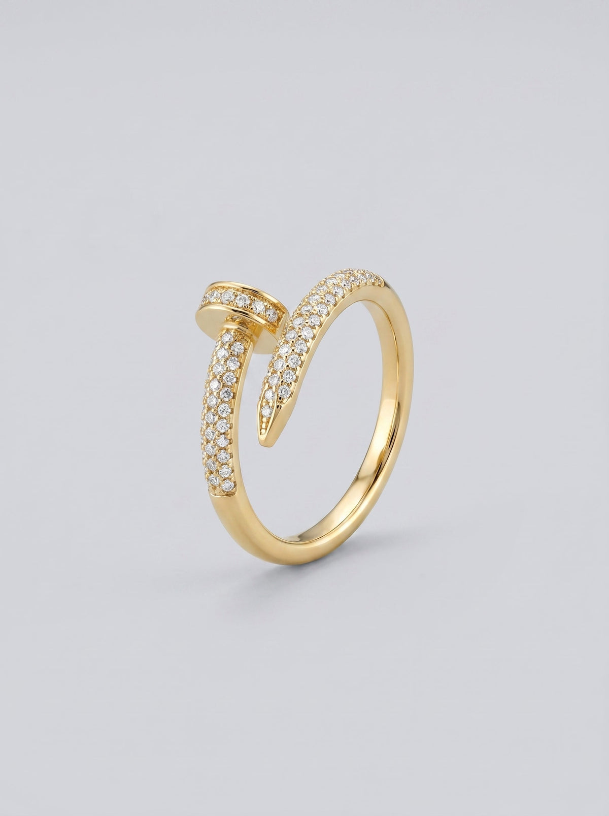 Anillo dorado con detalles en diamante sobre fondo gris claro.
