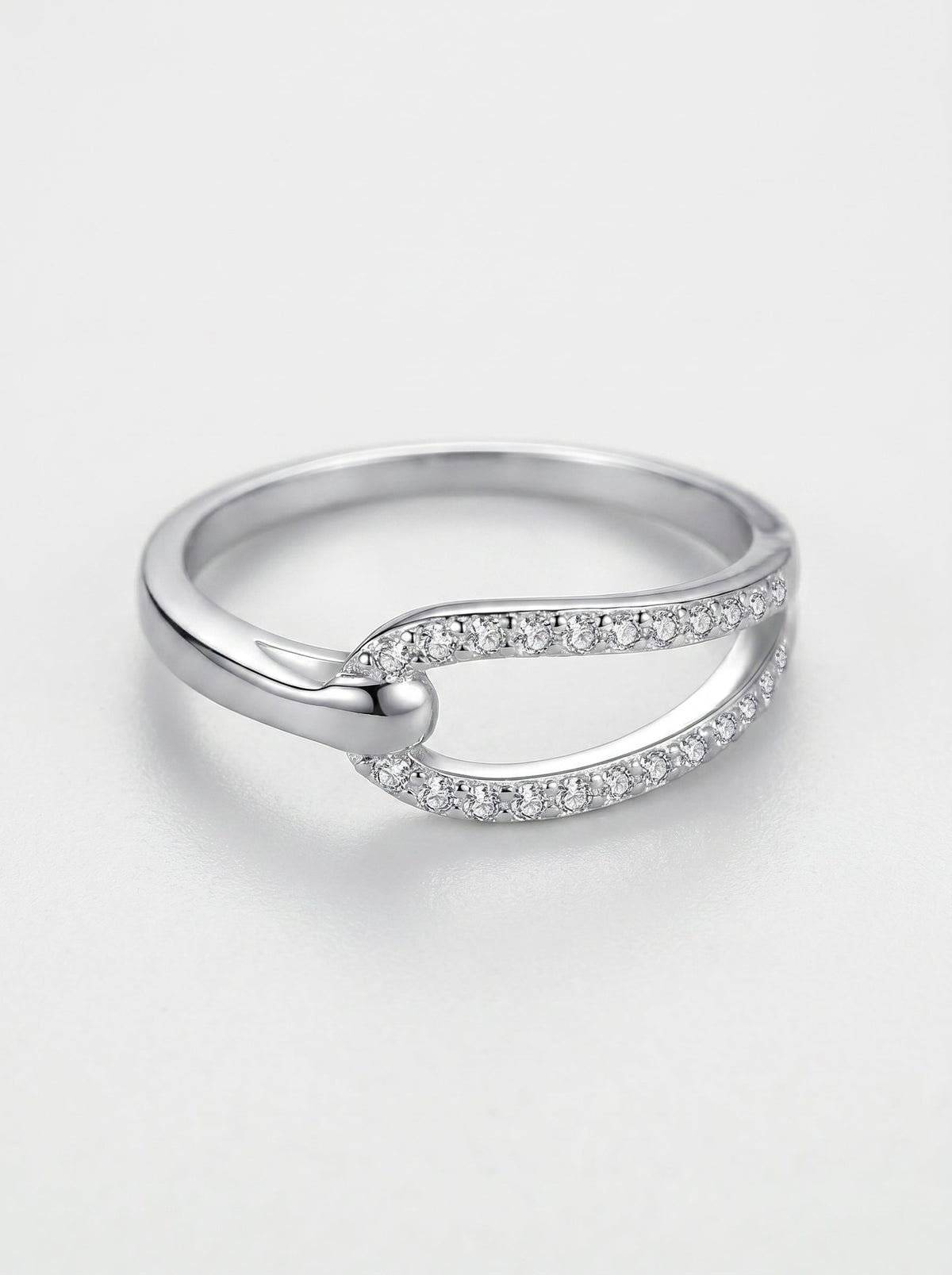 Anillo de plata con pequeños diamantes sobre fondo gris claro.