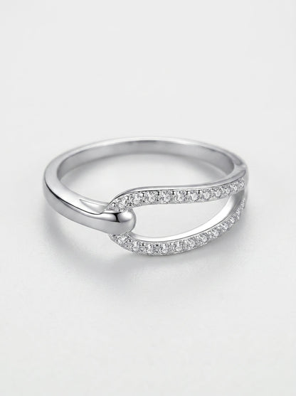 Anillo de plata con pequeños diamantes sobre fondo gris claro.