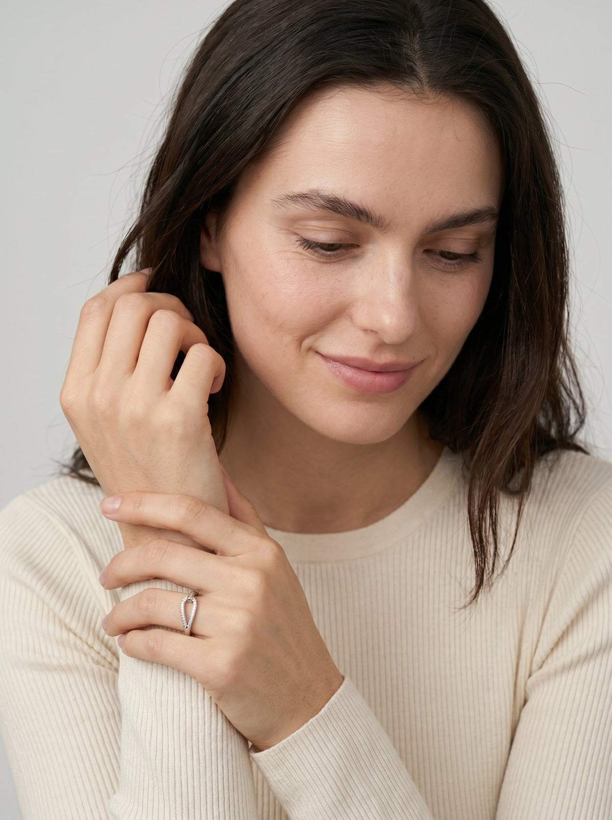 Mujer con un anillo en el dedo contra un fondo neutro.