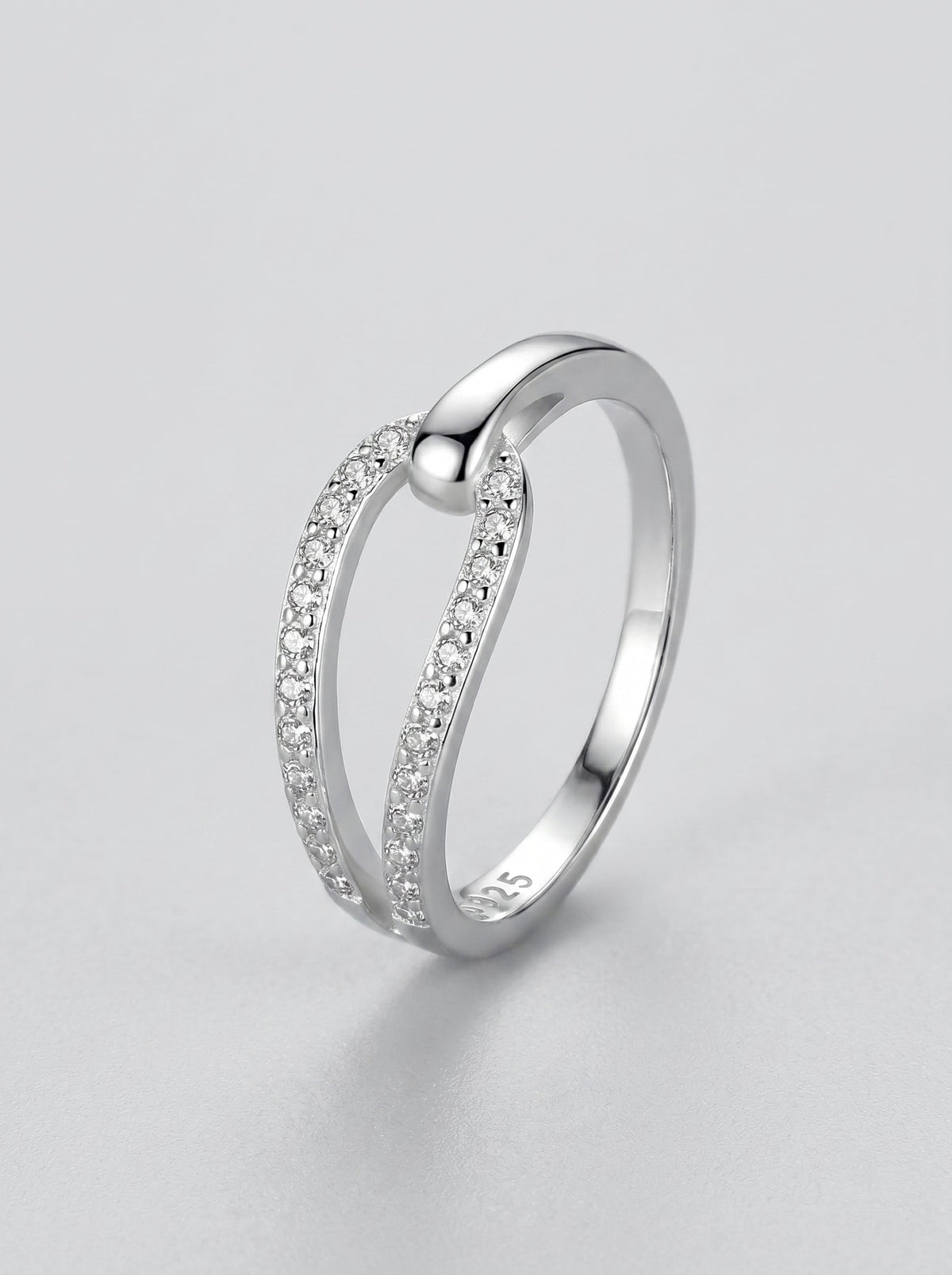 Anillo de plata con pequeños diamantes sobre fondo gris claro.