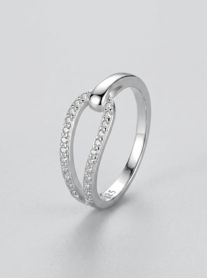 Anillo de plata con pequeños diamantes sobre fondo gris claro.