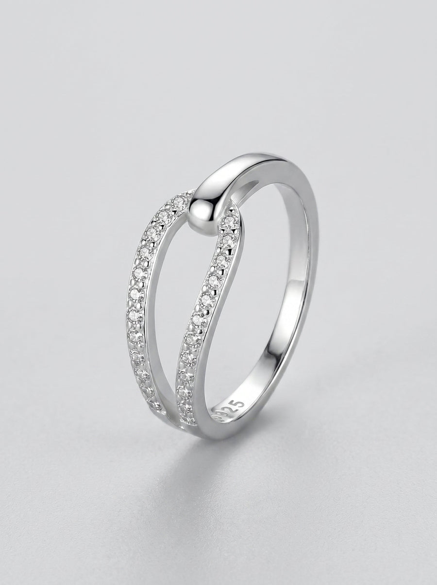 Anillo de plata con pequeños diamantes sobre fondo gris claro.
