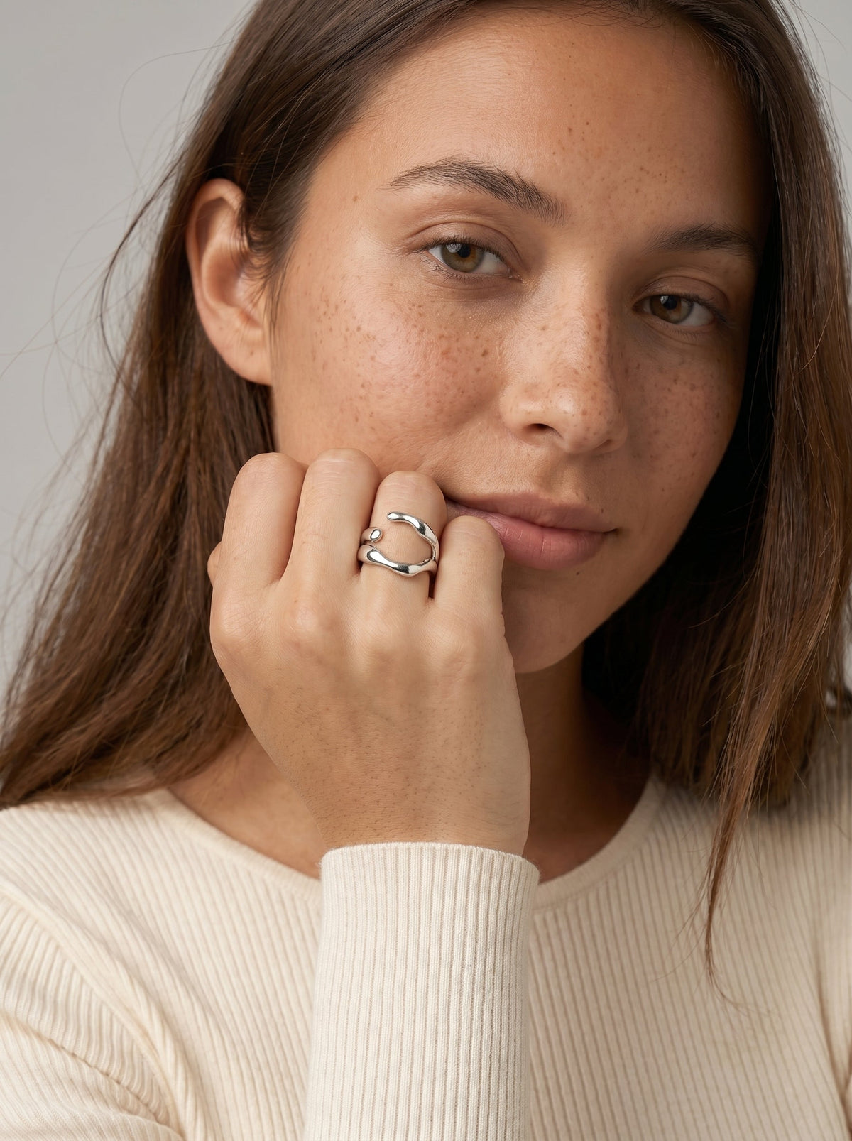 Mujer con un anillo sobre un fondo neutro
