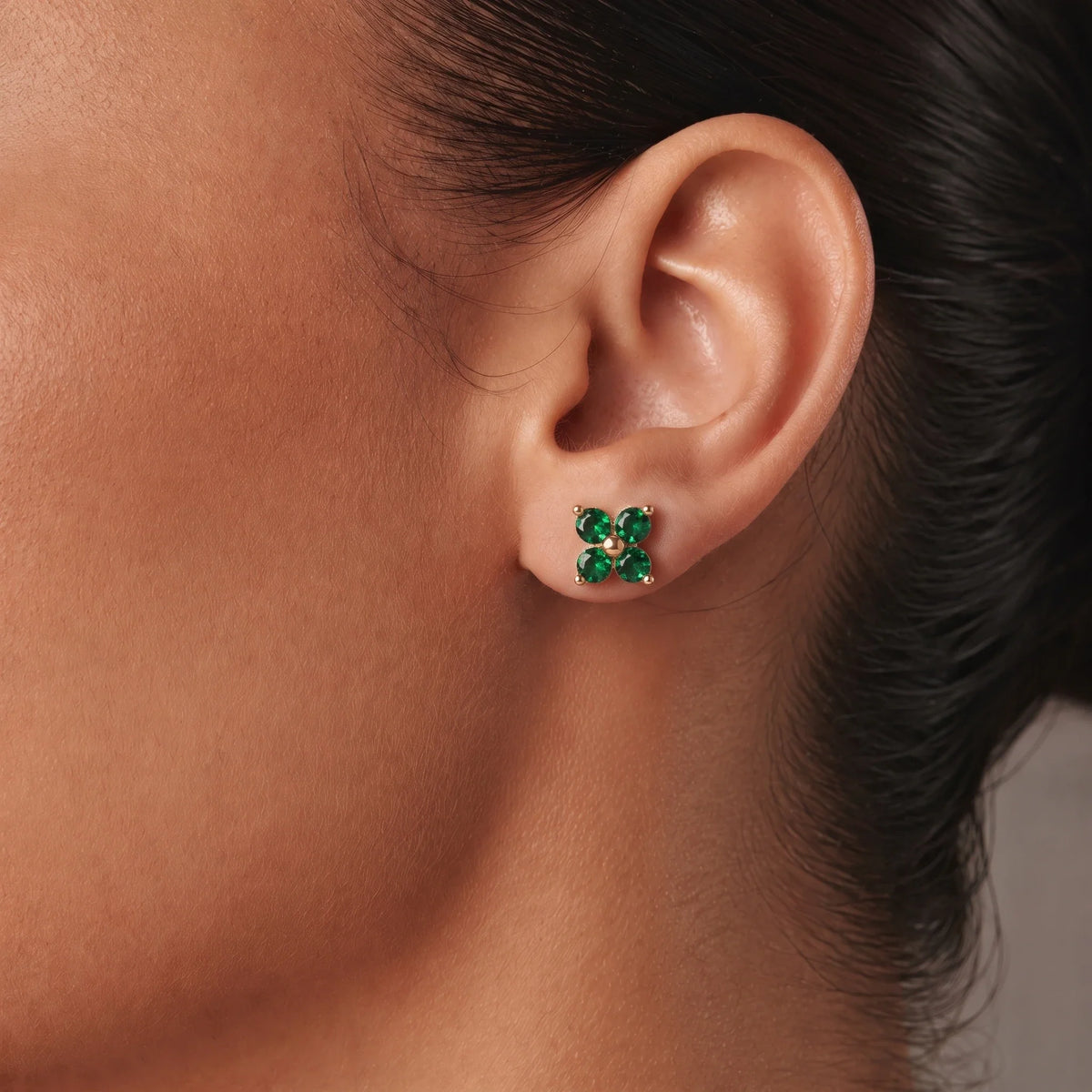Pendientes florales con piedra de nacimiento en uso — primer plano en la oreja