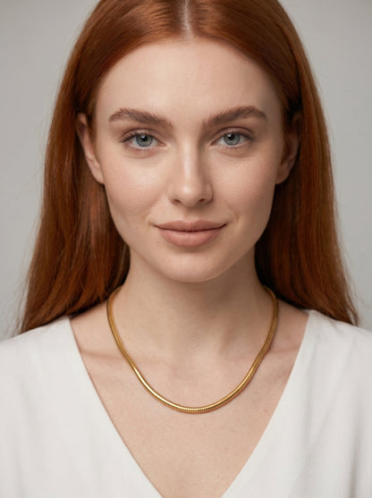 Collar dorado moderno con acabado texturizado y diseño minimalista, llevado por una modelo para un look elegante, artístico y sofisticado.