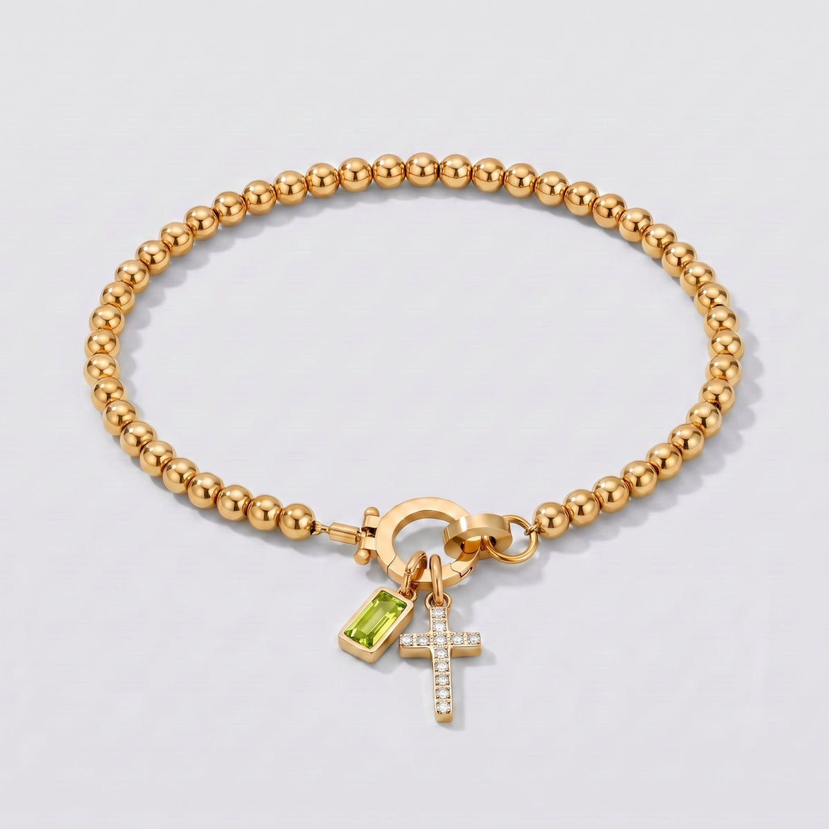 Pulsera dorada de cuentas con cruz y piedra de nacimiento peridoto de agosto.