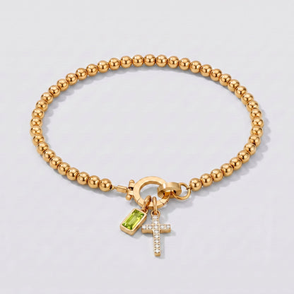 Pulsera dorada de cuentas con cruz y piedra de nacimiento peridoto de agosto.
